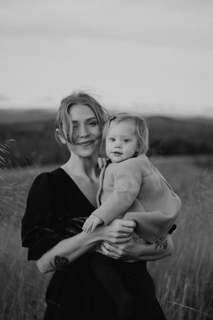 A serene black and white portrait of a mother with her daughter in an outdoor setting.